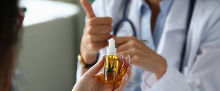 a woman holds a bottle of cbd oil as a doctor gives a thumbs up